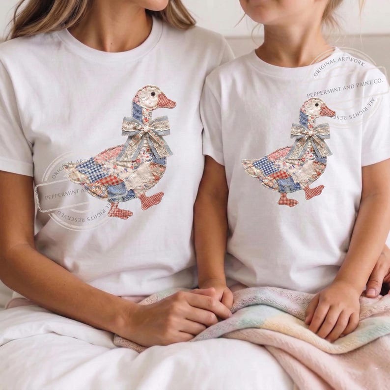 May include: White t-shirts featuring a patchwork goose design with a bow. The goose has a red beak and feet, and the patchwork includes blue, red, and cream patterns. The text "PEPPERMINT AND PAINT CO." is visible on the shirts.