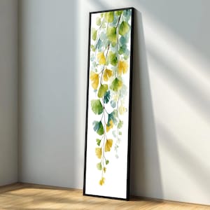 May include: A long, vertical framed art print featuring a watercolor painting of cascading ginkgo leaves. The leaves transition from yellow to green and blue against a white background. The frame is black.