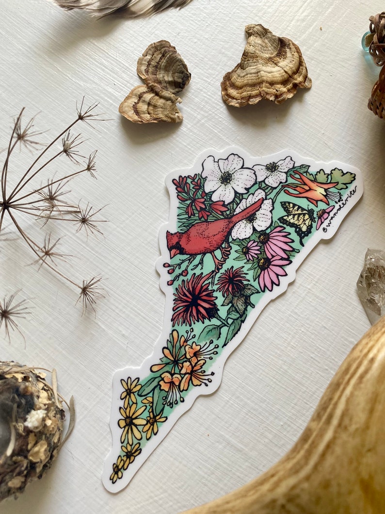 May include: A sticker featuring a green and white outline of a state with a red cardinal bird, white flowers, pink flowers, yellow flowers, and butterflies. The sticker has the text "@wanderwriter" in the bottom right corner.
