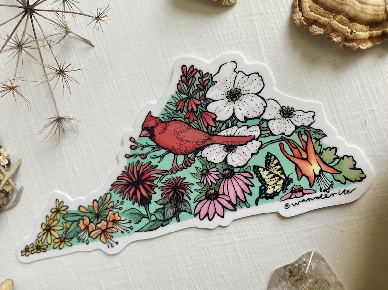 May include: A sticker depicting a red cardinal bird perched on a branch with a variety of flowers and butterflies. The flowers are pink, white, and red, and the butterflies are yellow and black. The sticker is shaped like the state of Virginia and has the text "wanderrite" in the bottom right corner.