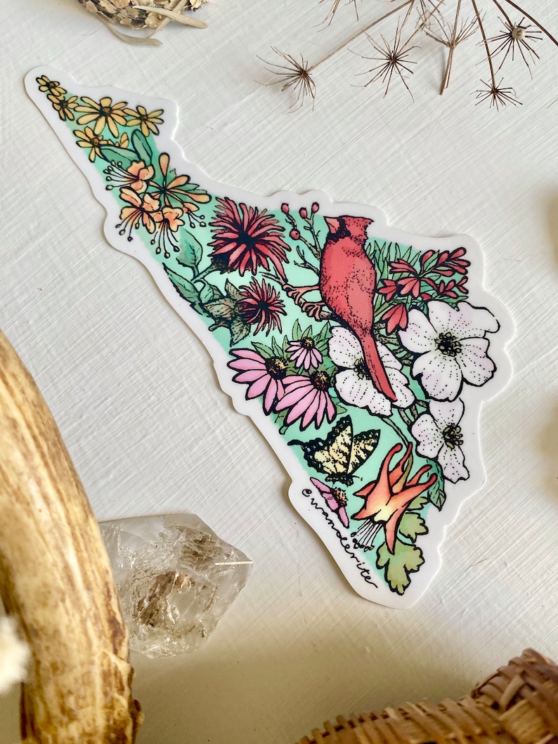 May include: A sticker featuring a red cardinal bird perched on a branch with pink, white, and yellow flowers. The background is a light green watercolour wash. The sticker has the text "wanderlite" at the bottom.