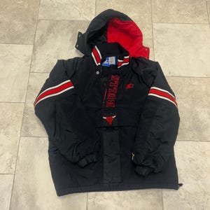 May include: Black and red Chicago Bulls Starter jacket with a hood. The jacket features red and white stripes on the sleeves and the word "BULLS" in red down the front. A red bull logo is also visible.