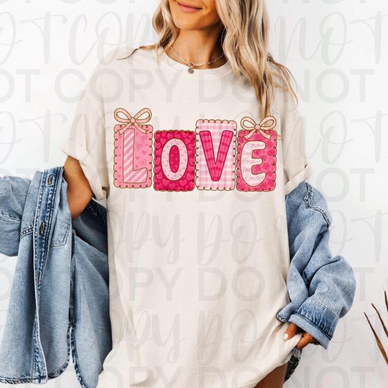 May include: Cream-colored t-shirt with the word "LOVE" in pink, each letter designed as a decorative block with bows. The letters feature patterns like stripes, hearts, and gingham. The shirt is worn with a denim jacket.
