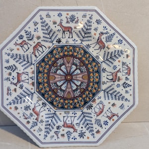 Puede incluir: Plato octogonal de cerámica con fondo blanco, con un diseño floral central en tonos azules, naranjas y marrones. El plato está decorado con motivos de ciervos y helechos en azul y marrón, creando una estética rústica inspirada en la naturaleza.