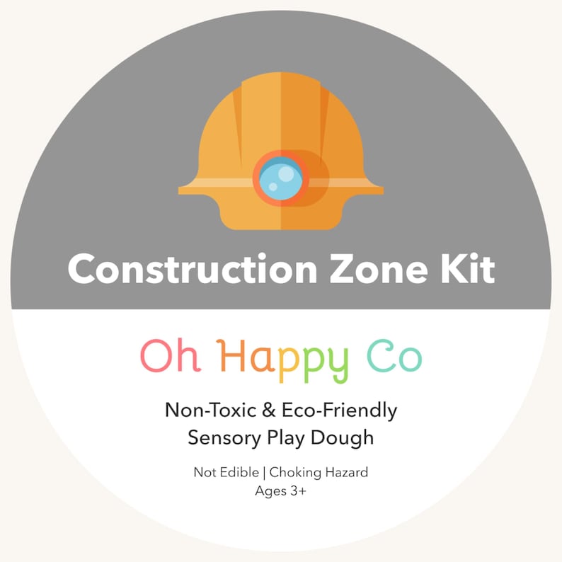 May include: A circular graphic with a gray background features an orange construction helmet icon. The text "Construction Zone Kit" is above the text "Oh Happy Co". Below are the words "Non-Toxic & Eco-Friendly Sensory Play Dough".