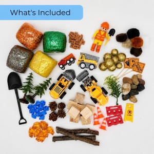 May include: A collection of construction-themed toys and accessories, including toy trucks, cones, rocks, and glittery blocks. A small figure of a construction worker is also included. The text "What's Included" is in a blue rectangle.