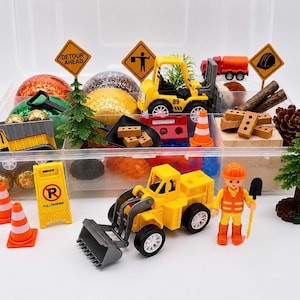 May include: A clear plastic container filled with toy construction vehicles, signs, cones, and a construction worker figurine. The set includes a yellow front-end loader, dump truck, and a red cement truck. The signs read "Detour Ahead" and "Full Parking".
