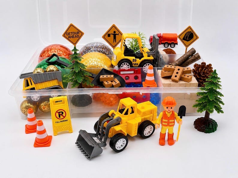 May include: A clear plastic container filled with toy construction vehicles, signs, cones, and a construction worker figurine. The set includes a yellow front-end loader, dump truck, and a red cement truck. The signs read "Detour Ahead" and "Full Parking".
