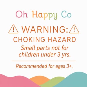 May include: A white safety warning sign with the text Oh Happy Co at the top. Below, orange warning triangles flank the text WARNING: CHOKING HAZARD. It states Small parts not for children under 3 yrs. and Recommended for ages 3+ with wavy color shapes.