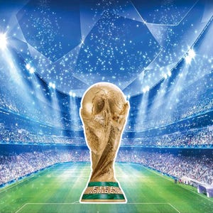 May include: A gold-colored FIFA World Cup trophy stands on a green and white base, with the words "FIFA WORLD CUP" in white. The trophy is set against a backdrop of a stadium filled with spectators and a blue sky.