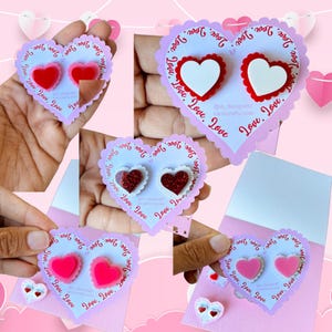 May include: Valentine's Day-themed heart-shaped cards with decorative heart-shaped embellishments. The cards feature scalloped edges and the word "Love" printed around the border. The embellishments include red, white, and glittery hearts.