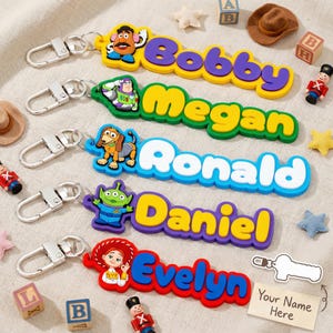 Puede incluir: Llaveros con nombres coloridos con personajes de dibujos animados y nombres como Bobby, Megan, Ronald, Daniel y Evelyn. Cada llavero tiene un cierre plateado y un diseño único con colores vibrantes. Un accesorio divertido.