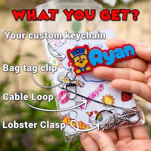 May include: A clear plastic bag containing a custom keychain with the name "Ryan" in blue letters. The keychain features a cartoon character and includes a bag tag clip, cable loop, and lobster clasp. Text in the image reads "WHAT YOU GET?"
