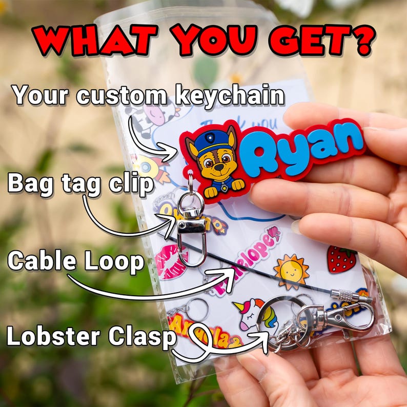 May include: A clear plastic bag containing a custom keychain with the name "Ryan" in blue letters. The keychain features a cartoon character and includes a bag tag clip, cable loop, and lobster clasp. Text in the image reads "WHAT YOU GET?"