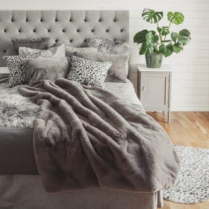 Könnte beinhalten: Ein Set aus drei Keramikbechern mit gesprenkelter, matter Oberfläche. Jeder Becher hat eine andere Farbe: Hellblau, Creme und Grau. Die Becher haben ein schlichtes, modernes Design.
