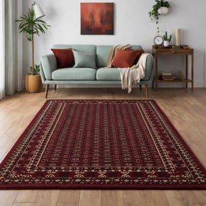 Può includere: Un tappeto rettangolare bordeaux con un intricato motivo geometrico. Il tappeto presenta un design centrale di forme ripetute e un bordo con un accento color crema. Il tappeto è posizionato su un pavimento in legno in un soggiorno.