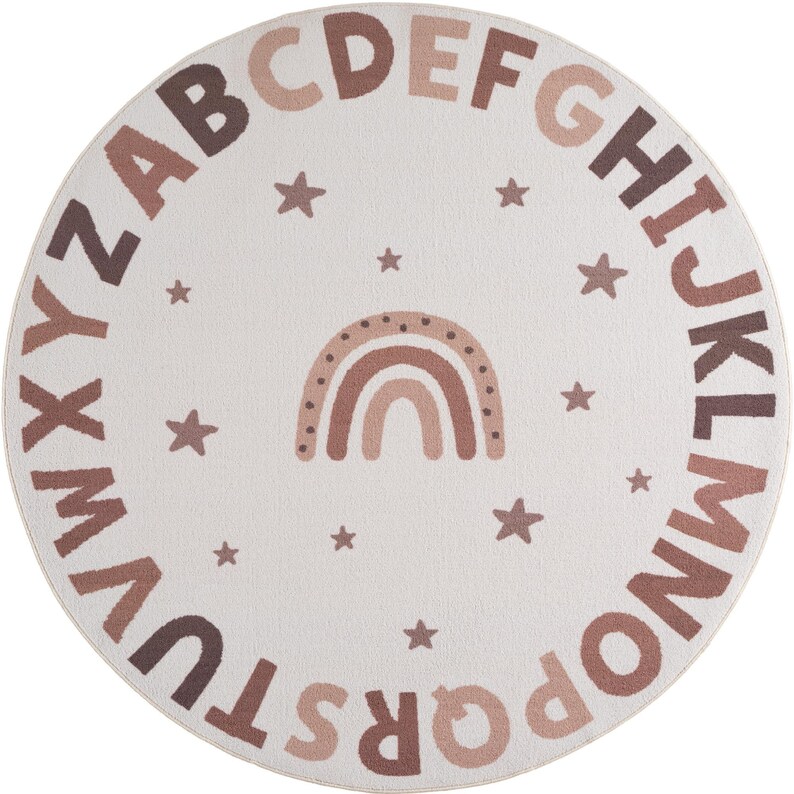 May include: Round, off-white rug featuring the alphabet in various shades of brown around the perimeter. A brown rainbow and stars are in the center. The rug is designed for a nursery or playroom.