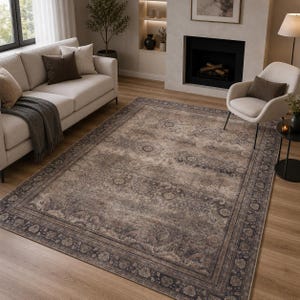 Könnte beinhalten: Ein rechteckiger Teppich mit einem abgenutzten, verblassten Muster in den Farben Anthrazit, Taupe und Beige. Der Teppich zeigt ein zentrales Medaillon-Design, das von einer komplizierten floralen Bordüre umgeben ist und den Boden bedeckt.