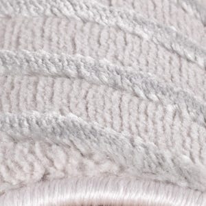 May include: Close-up of a soft, textured rug in shades of white and light gray. The rug features a pattern of diagonal, raised lines, creating a plush and inviting appearance. The fibers appear dense and luxurious, suggesting comfort and warmth.