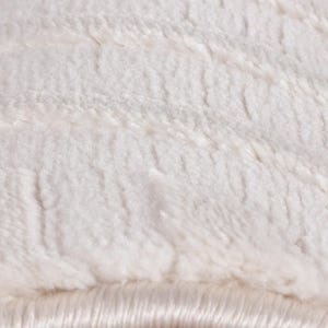May include: Close-up of a soft, white, plush fabric with a textured surface. The material has a fluffy appearance with visible fibers and a subtle sheen, suggesting a cozy and comfortable texture.
