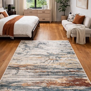 May include: A rectangular area rug with a distressed design. The rug features a mix of colors, including blue, brown, and cream, creating a textured, abstract pattern. It is placed on a hardwood floor in a bedroom setting.