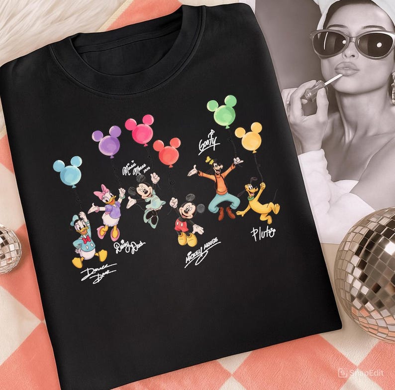 May include: Black crew neck sweatshirt featuring a colorful graphic of Disney characters holding balloon bouquets. The characters include Donald Duck, Daisy Duck, Minnie Mouse, Mickey Mouse, Goofy, and Pluto. The characters' names are written below them.