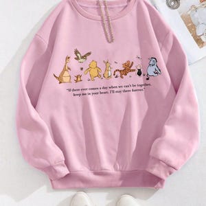 以下が含まれることがあります： 薄いピンク色のスウェットシャツ。カンガルー、クマ、トラ、ペンギンなどの漫画のキャラクターが描かれています。「If there ever comes a day when we can't be together, keep me in your heart. I'll stay there forever.」というテキストがプリントされています。