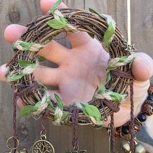 Close-up of the woven vine wreath and leafy wrapping of a handmade witch bell charm, showing the detailed craftsmanship.