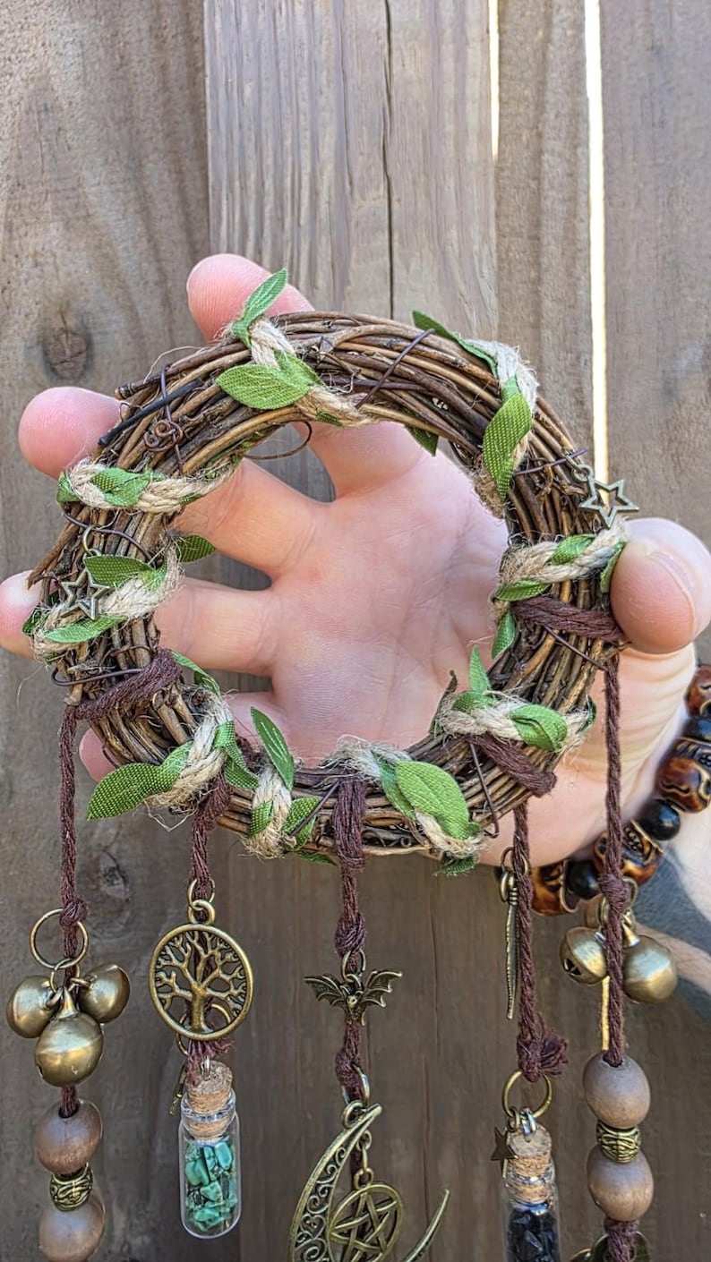 Close-up of the woven vine wreath and leafy wrapping of a handmade witch bell charm, showing the detailed craftsmanship.