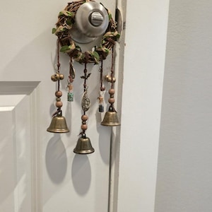 Witch bells hanging on a door handle as protective home décor, featuring bronze bells, charms, and gemstone vials