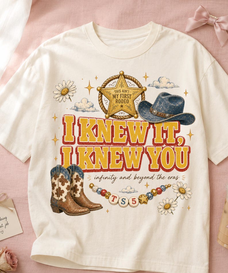 以下が含まれることがあります： クリーム色のTシャツで、'THIS AIN'T MY FIRST RODEO'と書かれた金色の保安官バッジ、青いカウボーイハット、茶色の柄入りカウボーイブーツ、デイジーの花、'TS5'と書かれたビーズの紐のグラフィックプリントが施されています。テキストは'I KNEW IT, I KNEW YOU'および'infinity and beyond the eras'と書かれています。