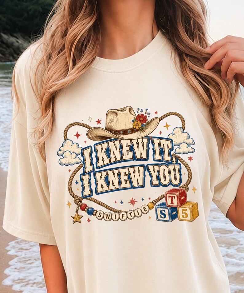 以下が含まれることがあります： カウボーイハット、投げ縄、そして「I KNEW IT, I KNEW YOU」という文字がプリントされたクリーム色のTシャツ。デザインには小さな雲、星、SWIFTIEと綴られたビーズの紐、T、S、5と書かれた2つの積み木が含まれています。