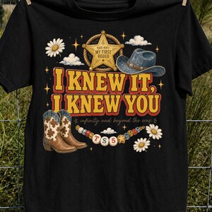 以下が含まれることがあります： 「I KNEW IT, I KNEW YOU」、「THIS AIN'T MY FIRST RODEO」、「infinity and beyond the eras」というテキストがプリントされた黒いTシャツ。保安官のバッジ、カウボーイハット、カウボーイブーツ、デイジーの花、ビーズが描かれたグラフィックデザインが特徴です。