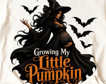 May include: A white t-shirt featuring a graphic of a pregnant witch in a black gown and pointed hat, surrounded by black bats. The text reads Growing My Little Pumpkin in white and orange lettering. The design is centered on the front of the shirt.