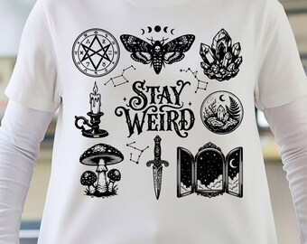May include: A white t-shirt featuring a black graphic print with the text "STAY WEIRD" at the center. The design includes illustrations of a moth, a crystal cluster, a candle, a mushroom, a dagger, a mirror, and celestial symbols.