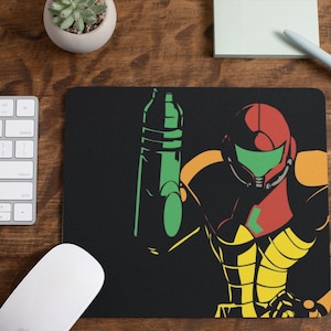 May include: Black rectangular mousepad featuring a stylized illustration of a video game character in a red, green, yellow, and orange color scheme. A green weapon is also depicted. A white keyboard and mouse are visible.