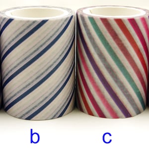Op de afbeelding: Vier rollen decoratieve plakband op een rij, gelabeld a, b, c en d. Rol a heeft paarse en witte diagonale strepen, rol b heeft blauwe en witte diagonale strepen, rol c heeft veelkleurige diagonale strepen en rol d heeft een roze en paars ruitpatroon.