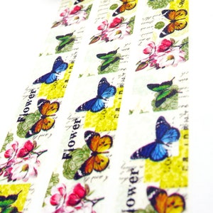 May include: Decorative washi tape featuring a repeating pattern of butterflies, flowers, and the word "Flower". The butterflies are in shades of blue, orange, and green. The flowers are pink and white. The background has a vintage, handwritten script design.