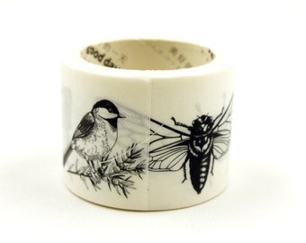 May include: A roll of white washi tape with black and white illustrations of a bird and an insect. The tape has the text "good day" printed on it.