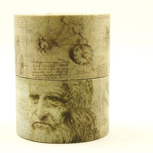 May include: Two-piece cylindrical container with a vintage design. The top section features a sketch of a machine, while the bottom displays a portrait of a man. The container has a sepia tone, giving it an aged appearance.