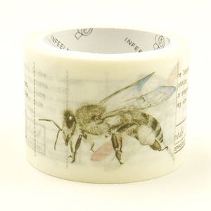 May include: A roll of decorative washi tape featuring a detailed illustration of a bee with blue-tipped wings. The tape has a cream-colored background with faint text and dotted lines. The tape is perfect for crafts and scrapbooking.