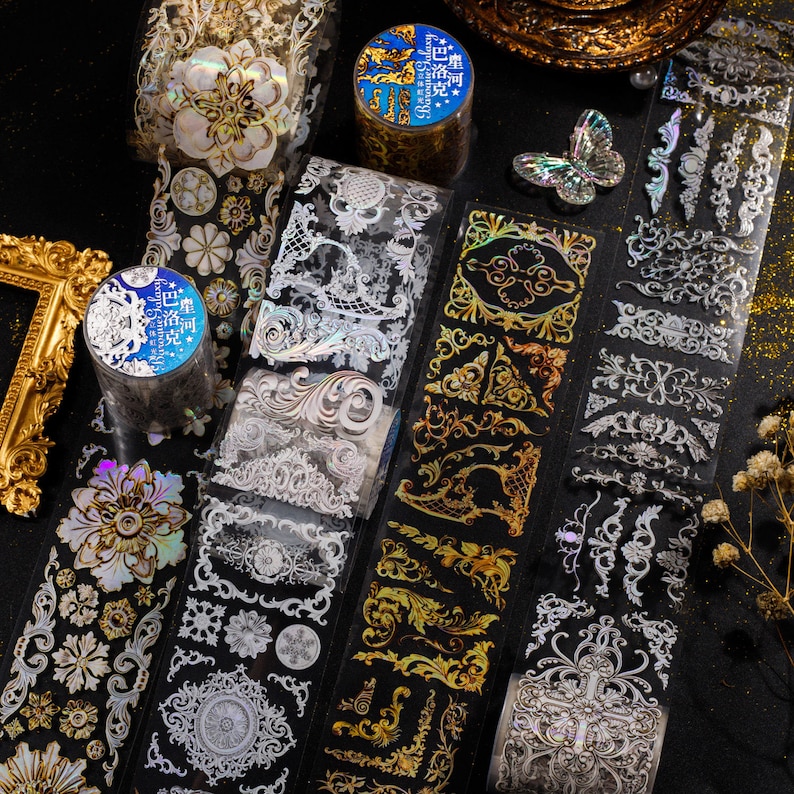 May include: Assortment of decorative washi tapes featuring intricate gold and silver designs. The tapes have a holographic finish and are perfect for adding a touch of elegance to crafts, journals, and other projects.