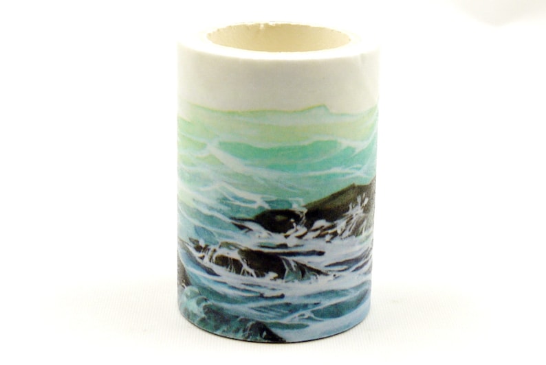 May include: A roll of washi tape with a blue and green ocean wave design. The tape is on a white background.