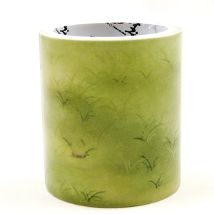 May include: A roll of washi tape with a green grassy design. The tape features a light green background with darker green blades of grass scattered across the surface. The brand name "TREASURE" is printed on the inside of the roll.