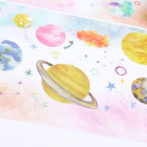 Könnte beinhalten: Ein farbenfrohes Washi-Tape mit Weltraumthema. Das Band zeigt Planeten, Sterne und Sternbilder auf einem rosa und blauen Aquarellhintergrund.