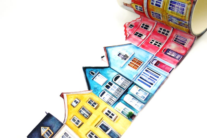 May include: A roll of washi tape featuring a watercolor illustration of colorful European-style houses. The houses are painted in shades of yellow, blue, red, and orange, with white window frames and doors. The tape is on a white background.