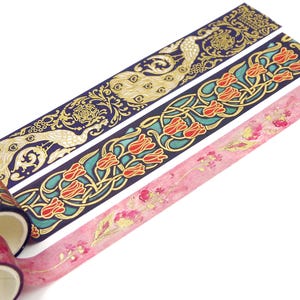 Pu&ograve; includere: Tre rotoli di nastro washi decorativo con dettagli dorati. Il primo rotolo presenta un design di pavone su uno sfondo blu scuro. Il secondo rotolo presenta un design floreale con tulipani rossi su uno sfondo blu scuro. Il terzo rotolo presenta un design floreale con dettagli rosa e dorati su uno sfondo bianco.
