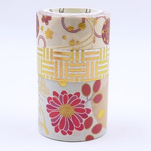 May include: A stack of decorative washi tape rolls. The top roll features a floral pattern with burgundy and gold accents. The middle roll has a gold geometric design, and the bottom roll displays a large red flower.