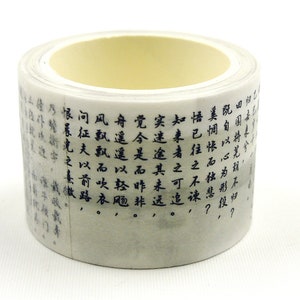 Puede incluir: Un rollo de cinta washi con un fondo gris claro y caligrafía china en tinta negra. La cinta está enrollada alrededor de un núcleo amarillo claro. El texto es parcialmente visible.