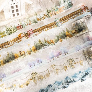Può includere: Diversi rotoli di nastro adesivo washi decorativo con scene invernali. I disegni includono paesaggi innevati con case, pupazzi di neve, cervi e alberi. I nastri hanno uno stile acquerello con morbidi blu, verdi e marroni.